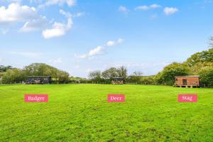eine grasbewachsene Fläche mit drei verschiedenen Schildern darauf in der Unterkunft Stag Shepherds Hut in Hartfield