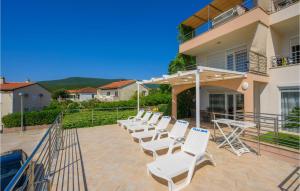 a row of white chairs sitting on a patio at Lovely Apartment In Sreser With House Sea View in Sreser +19 photos