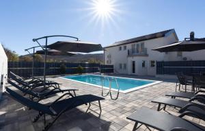 een zwembad met stoelen en parasols naast een gebouw bij Awesome Home In Imotski in Lokvičič