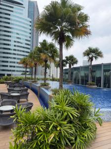 a pool with chairs and palm trees on a building at Soho suites klcc by Kualalampur twin tower vibes in Kuala Lumpur