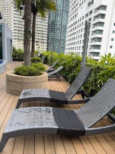 a deck with chairs and palm trees and buildings at Soho suites klcc by Kualalampur twin tower vibes in Kuala Lumpur