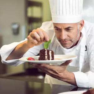 un chef mangeant un morceau de gâteau dans une assiette dans l'établissement Tinamar Selections, à Perivolos