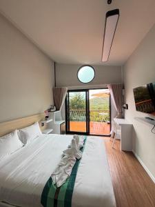 a bedroom with a bed and a large window at Two Tree Cafe At Suanmuangthong 