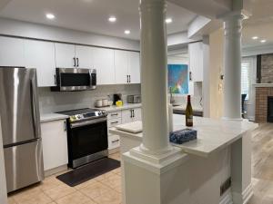 eine Küche mit weißen Schränken und einem Herd mit Backofen in der Unterkunft House of 3 Bed 3 Wash-Crib-King Bed-85' TV-Wrkspce in Oakville