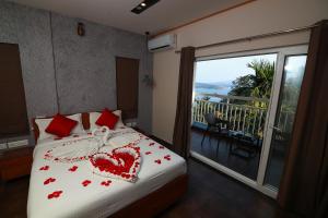 een slaapkamer met een bed met een hartvormig kussen en een balkon bij Bonita Banasura in Vythiri