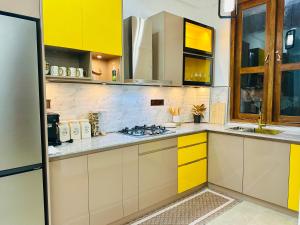 une cuisine avec des placards jaunes et blancs et une cuisinière dans l'établissement Golden Villa, à Wayikkal