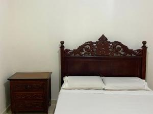 Casa no centro histórico de São João del- Rei في ساو جواو ديل ري: سرير مع اللوح الأمامي الخشبي بجوار خزانة