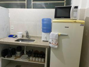 a small kitchen with a microwave on top of a refrigerator at Casa no centro histórico de São João del- Rei in São João del Rei