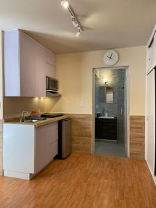 Una cocina con gabinetes blancos y un reloj en la pared. en Departamento Bonito cama Queen, con acceso privado, en Ramos Arizpe