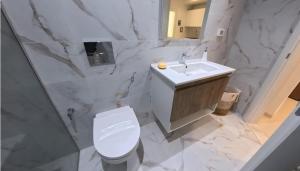 a white bathroom with a toilet and a sink at Farah in Sousse