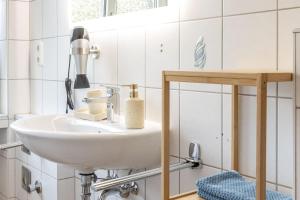 un lavabo blanc dans une salle de bain avec du carrelage blanc dans l'établissement Romantische Wohnung in der Moselregion, à Treis-Karden 27 autres photos