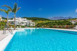 een groot zwembad met palmbomen en een huis bij Alcazaba Lagoon Apartment with Private Beach, Pools, Gym, Sauna, Hot Tub & Fully Equipped Kitchen in Casares
