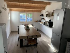 eine Küche mit einem Tisch mit Stühlen und einem Kühlschrank in der Unterkunft Maison de vacances , idéale pour famille avec accès plage et spa in Barbâtre