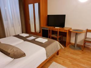 a bedroom with a bed and a desk with a television at Garni Hotel Keltika in Izola