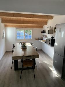 eine Küche und ein Esszimmer mit einem Tisch und einem Kühlschrank in der Unterkunft Maison de vacances , idéale pour famille avec accès plage et spa in Barbâtre + 14 Fotos