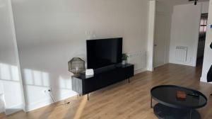 a living room with a flat screen tv and a table at LAIDA BEACH by Urdaibai Experience in Ibarrangelu