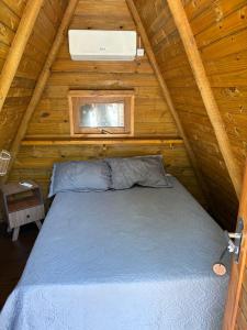 a bed in a wooden cabin with a window at Sitio Meu Refúgio Paracuru in Paracuru