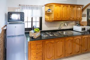 a kitchen with wooden cabinets and a white refrigerator at Ocean views "Las Garzas" in Sardina