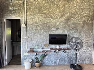 Zimmer mit einer Wand, einem TV und einem Ventilator in der Unterkunft pilokhillhouse บ้านอีต่องเหมืองปิล็อก in Ban Pilok Khi