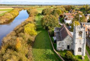 an aerial view of an old church next to a river at Historic Riverside House - Village, River Walks & Easy York Access in Cawood