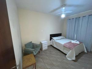 a bedroom with a bed and a chair at Cantinho do Sossego - Piscina com Hidro! in São Lourenço