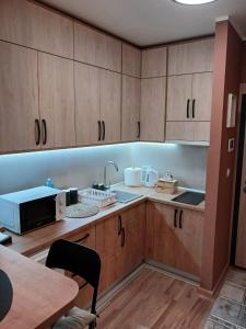 Una cocina con armarios de madera, fregadero y microondas. en Studio DORA SS, en Stari Banovci 18 fotos más