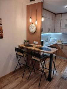Una cocina con una mesa con sillas y un reloj en la pared. en Studio DORA SS, en Stari Banovci