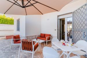un patio avec tables, chaises et un parasol dans l'établissement Villa Greta, à Isola della Malva