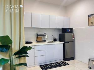 a small kitchen with white cabinets and a refrigerator at ITCC Manhattan Suites By Coastal Charm in Penampang +9 photos