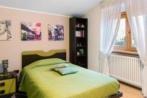 Un dormitorio con una cama verde y una ventana. en Casa Vacanze Dal Castelin, en Valtellina