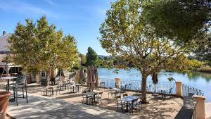 eine Gruppe von Tischen und Stühlen neben einem Fluss in der Unterkunft Maison 3 pièces domaine golf Pont Royal in Mallemort