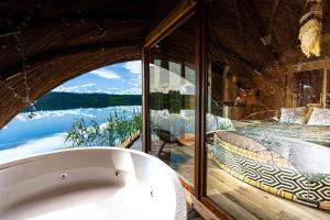 a bath tub in a room with a large window at Nameliai Miškuose in Molėtai