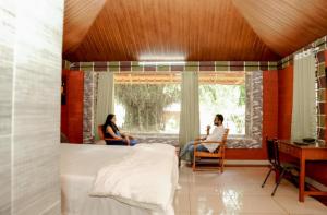 two people sitting in chairs in a room with a bed at Misty Night Wayanad Pool Resort in Wayanad