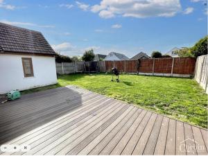 a person standing on a wooden deck in a yard at NexStay Bournemouth Retreat 5 Bed Luxe Bungalow in Bournemouth
