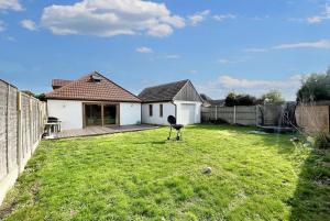 a yard with a house and a bird standing in the grass at NexStay Bournemouth Retreat 5 Bed Luxe Bungalow in Bournemouth