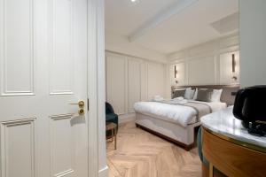 a white bedroom with a bed and a desk at GuestReady - The Fitzroy Hotel in London
