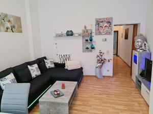 ein Wohnzimmer mit einer schwarzen Couch und einem Tisch in der Unterkunft Citystudio Neuwied mit Schlafgalerie bis 5 Gäste direkt am Luisenplatz in Neuwied