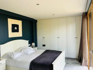a bedroom with a white bed and green walls at Villa Nature & Douets - aux portes du Mans - 5 chambres climatisées - piscine à débordement et terrain arboré d'1 hectare in La Chapelle-Saint-Aubin +9 photos