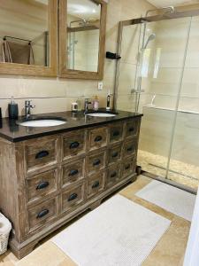 a bathroom with two sinks and a shower at Villa Nature & Douets - aux portes du Mans - 5 chambres climatisées - piscine à débordement et terrain arboré d'1 hectare in La Chapelle-Saint-Aubin