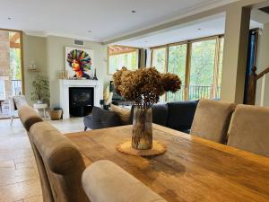 a vase of flowers on a wooden table in a living room at Villa Nature & Douets - aux portes du Mans - 5 chambres climatisées - piscine à débordement et terrain arboré d'1 hectare in La Chapelle-Saint-Aubin