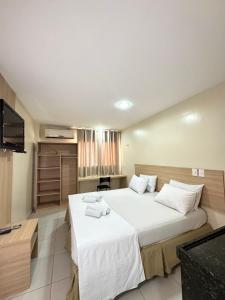 a bedroom with a large white bed and a flat screen tv at Arrey Fórmula Hotel - Itaueira in Piriperi