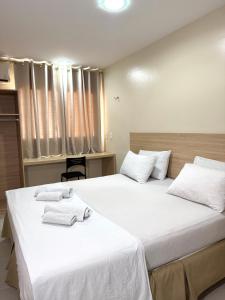 two beds in a room with white sheets and towels at Arrey Fórmula Hotel - Itaueira in Piriperi