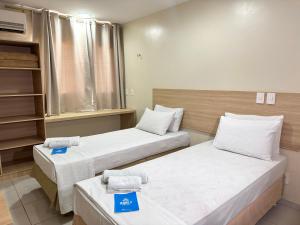 two beds in a hospital room with two blue signs at Arrey Fórmula Hotel - Itaueira in Piriperi