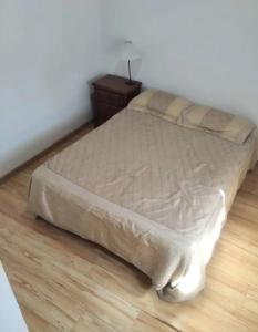 a bed in a bedroom with a wooden floor at Casa del campo in Mar del Plata +3 photos