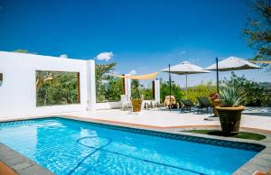 a swimming pool in a backyard with a patio with umbrellas at Trans Kalahari Inn in Voigtland