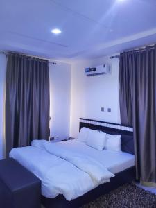 ポートハーコートにあるQuintessential Hotelの白いシーツと枕が付いた大きなベッドのある寝室