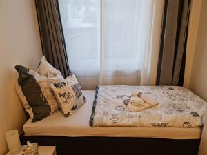 Bett in einem Zimmer mit Kissen und Fenster in der Unterkunft Citystudio Neuwied mit Schlafgalerie bis 5 Gäste direkt am Luisenplatz in Neuwied