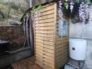 eine Toilette in einer Holzwand mit lila Blumen in der Unterkunft Cabane Sauna & Jacuzzi Hiver in Vaccili