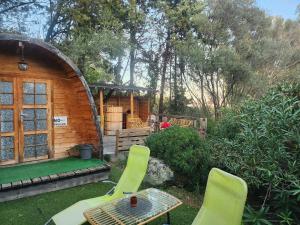 eine kleine Holzhütte mit grünen Stühlen und einem Tisch in der Unterkunft Cabane Sauna & Jacuzzi Hiver in Vaccili