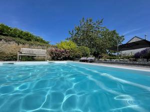 a blue swimming pool with a bench and an umbrella at Le Gîte du Pèlerin avec piscine in Florennes